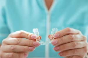 Woman holding transparent teeth aligner | King Orthodontics